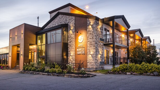 Un hotel moderno con fachada de piedra, ventanas amplias y un balcón.