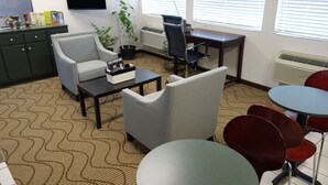 A room with a desk, two armchairs, a coffee table, and a TV mounted on the wall. - VIP Inn and Suites (Huntsville)
