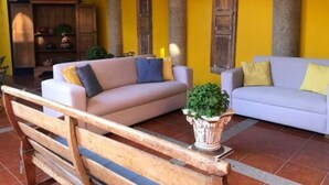 Un espacio de sala acogedor con dos sofás, un banco de madera y una planta en maceta.