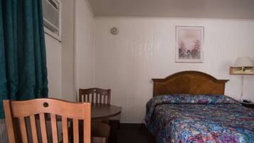 A hotel room with a wooden bed, a small table, and a chair.