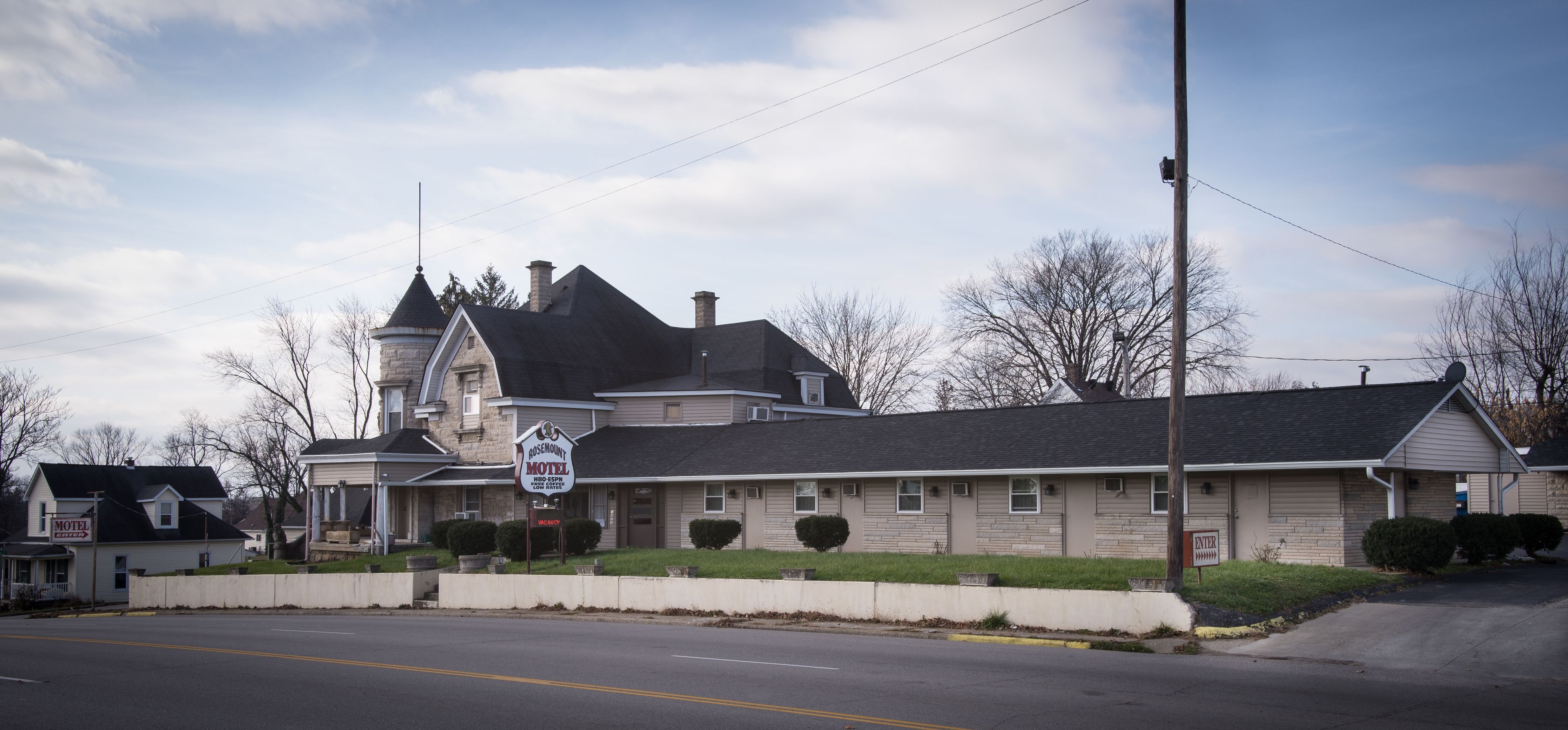 A motel with a large, historic building featuring a turret and a modern annex.