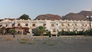A multi-story hotel with a consistent architectural style, featuring balconies and a central entrance with steps. - Triton Authentic Cretan Hotel (Minoa Pediada)