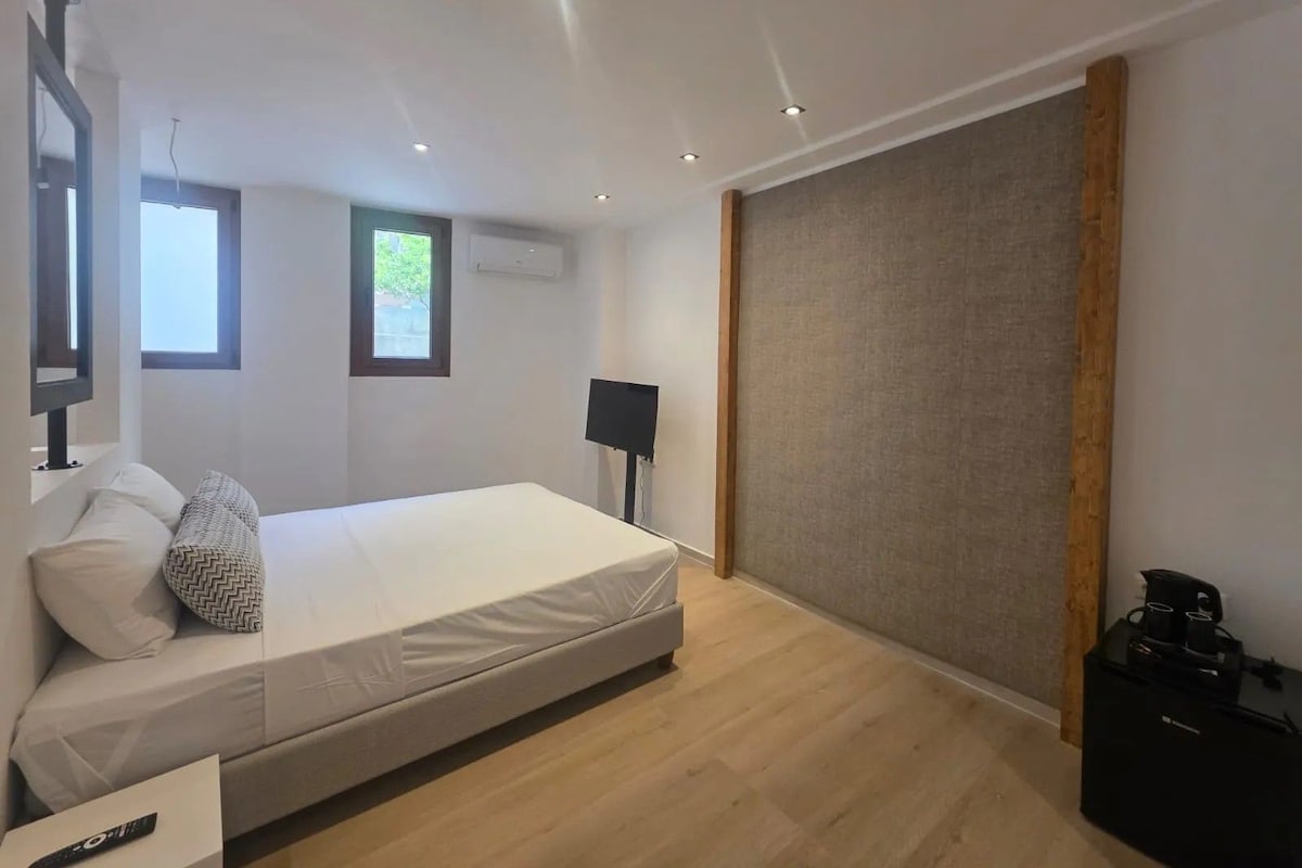 A modern bedroom with a bed, a TV, and a window.