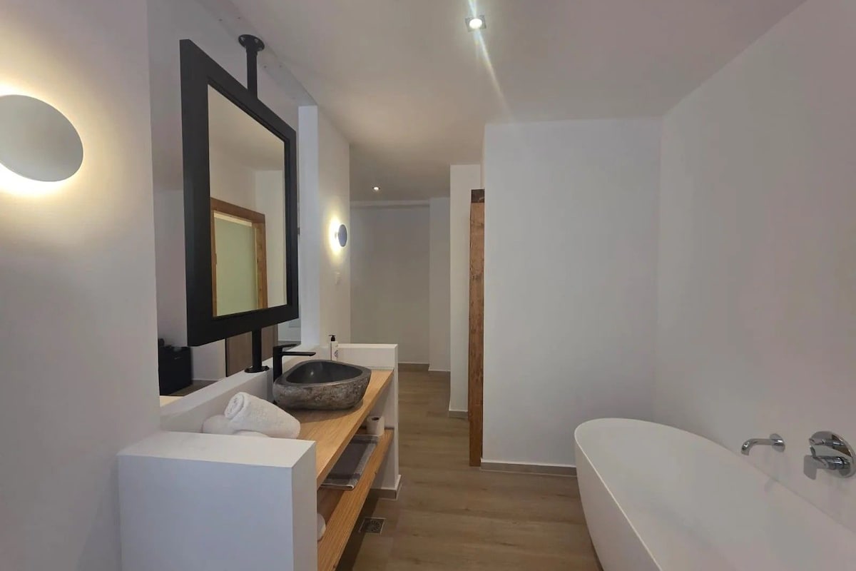 Un baño moderno con una bañera grande, un espejo y un tocador de madera.
