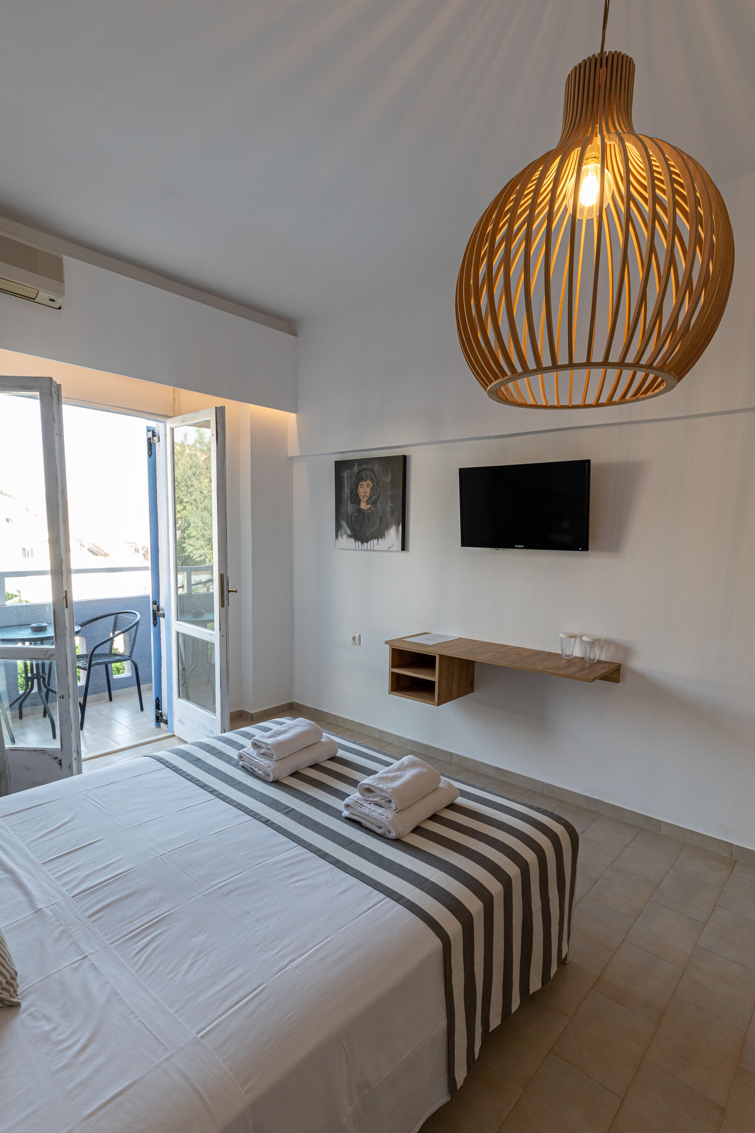 Een moderne slaapkamer met een bed, een televisie, een houten plank en een grote hanglamp.