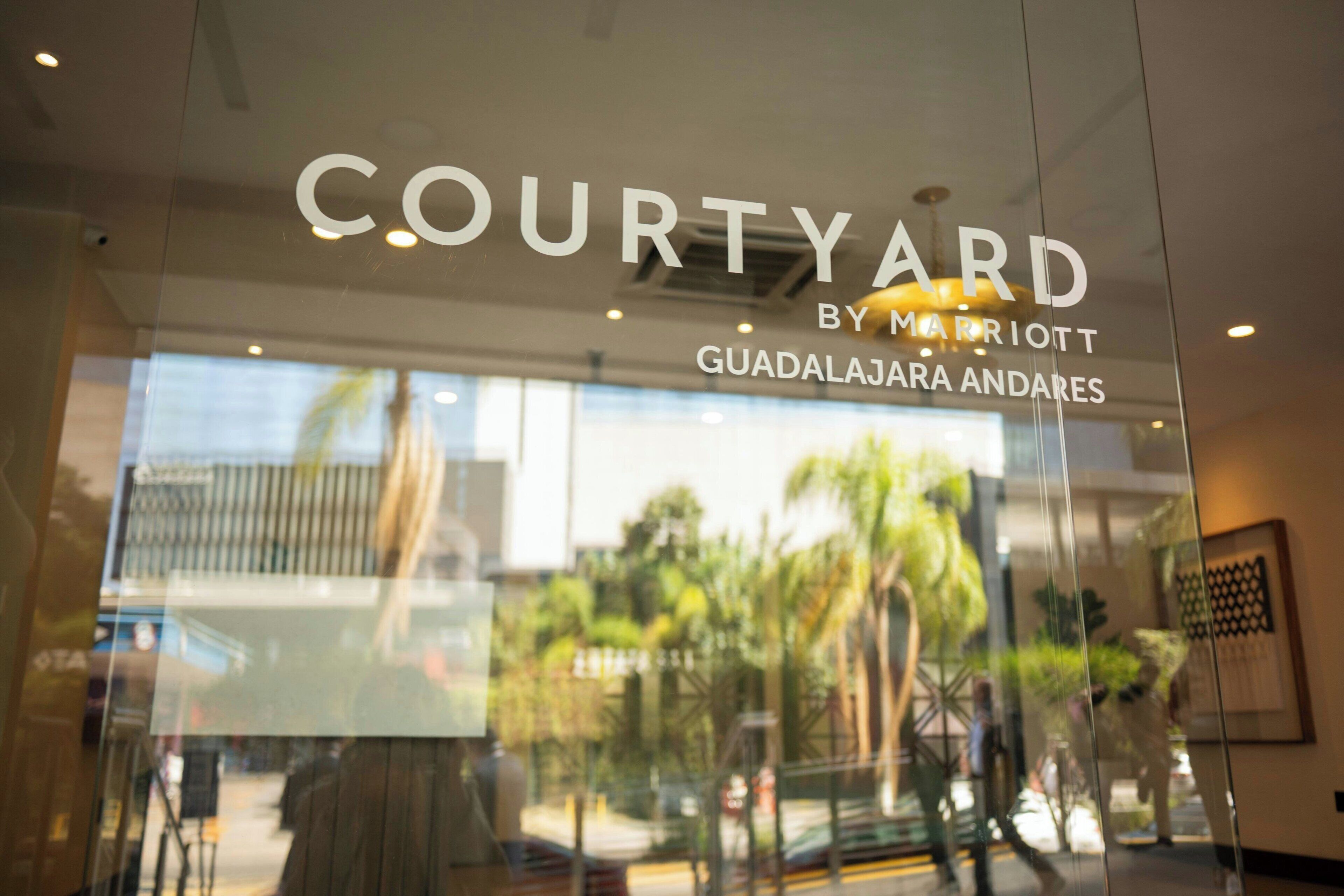 A glass entrance with the text 'COURTYARD BY MARRIOTT GUADALAJARA ANDARES'.