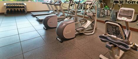Un gimnasio con cintas de correr, elípticas y una máquina de remo.