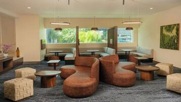 A modern lounge area with sofas, ottomans, and tables arranged for socializing.