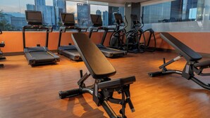 Ein Fitnessstudio mit Laufbändern, Crosstrainern und Bänken.