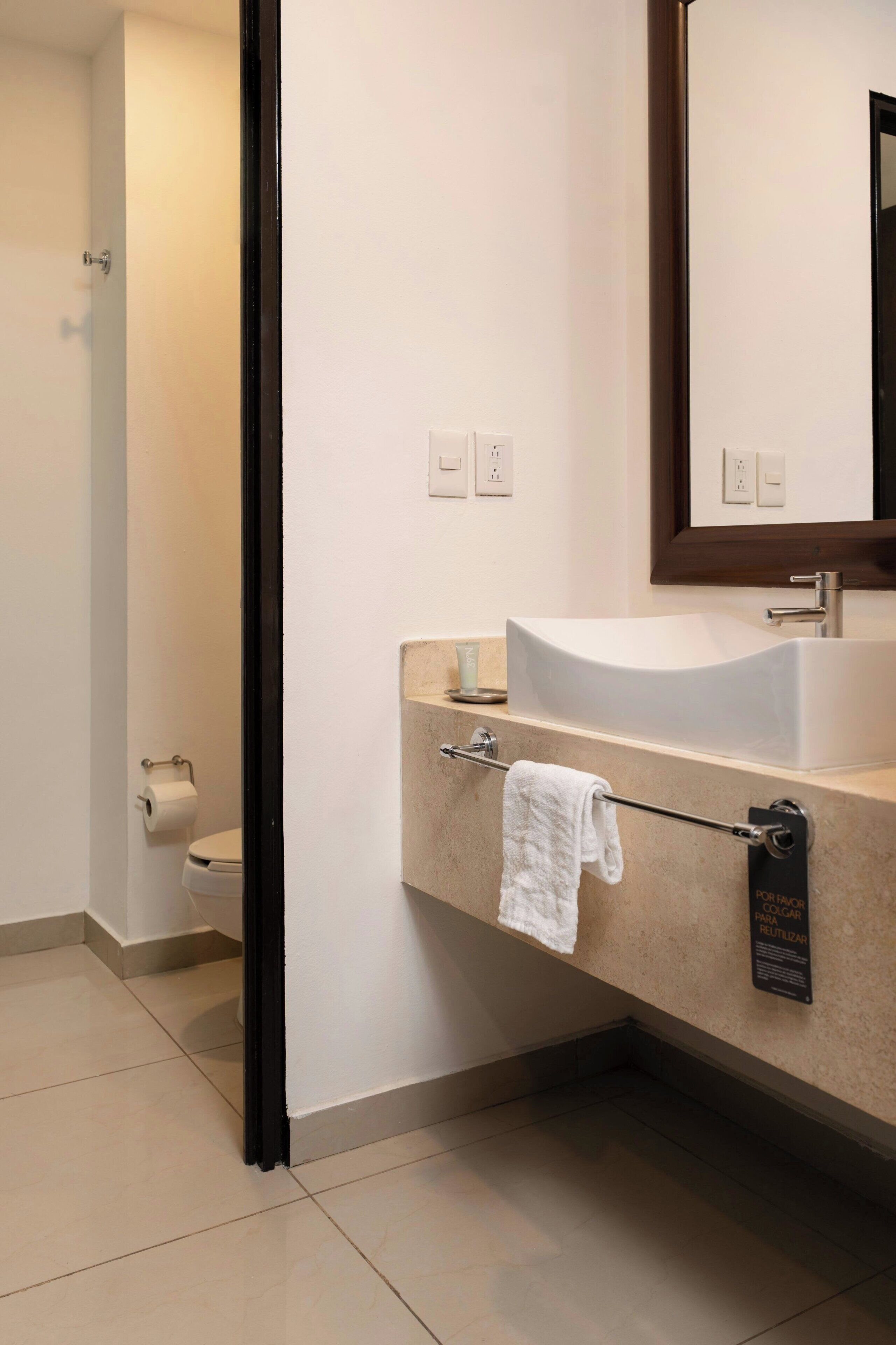A bathroom with a white sink, a towel rack, a toilet, and a mirror.