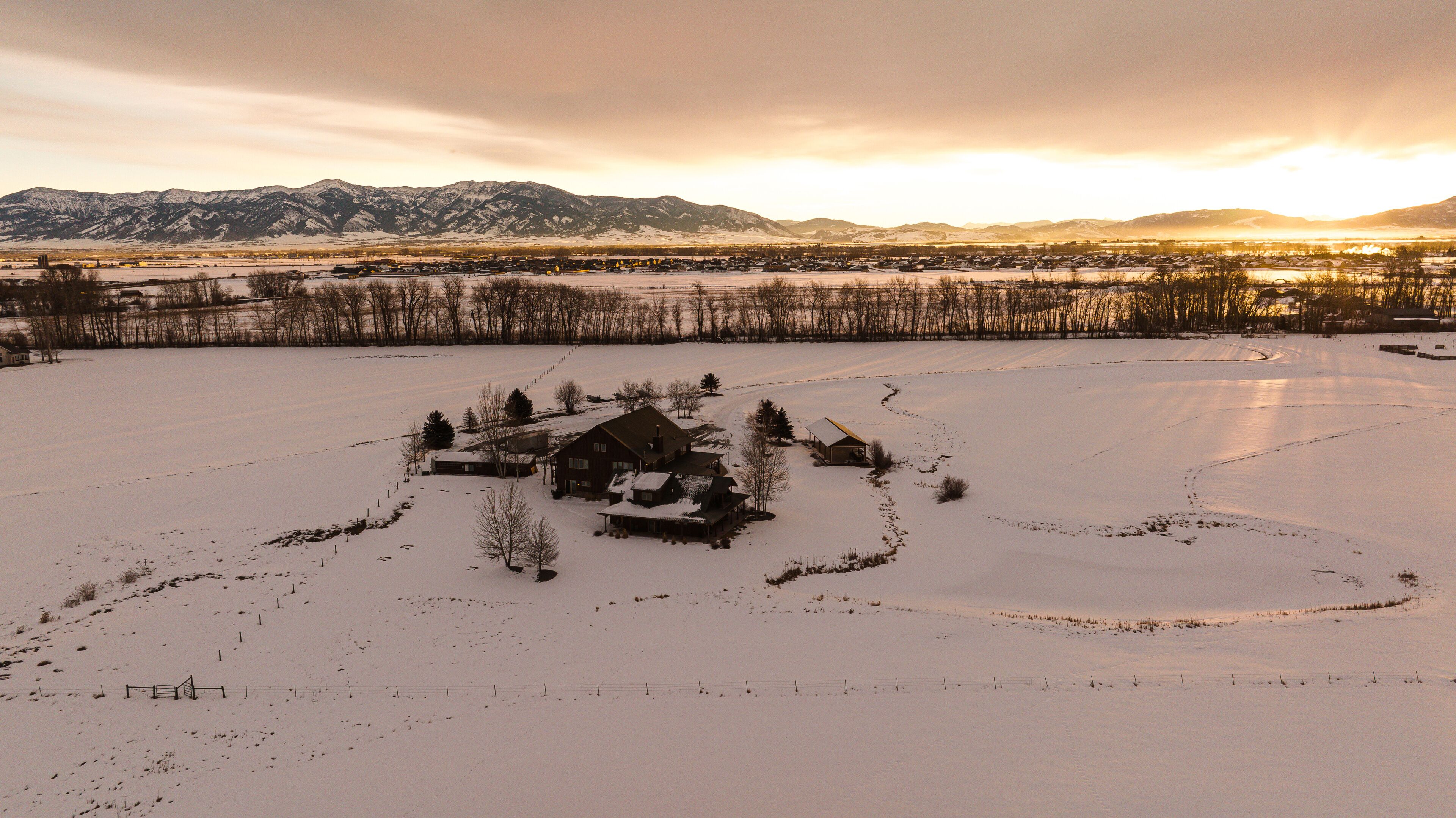 Schnee bedeckte Landschaft mit einer Holzhütte und umliegenden Bäumen.