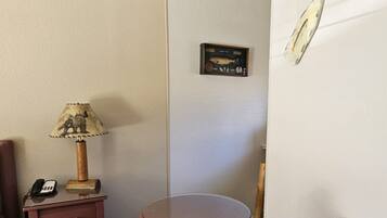 A wooden chair, a small table, a lamp, a phone, and a wall with fishing lures and a fish plaque.