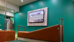 Een hotelkamer met een bed, een aan de muur bevestigde televisie en een accentmuur van baksteen.