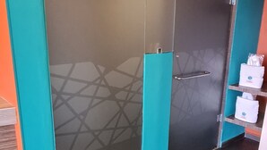 Een kamer met een grote schuifdeur, betegelde vloer en een plank met toiletartikelen.