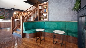 A modern interior with a wooden staircase, green upholstered seating, and a built-in bookshelf. - The Davis Downtown San Diego (San Diego)