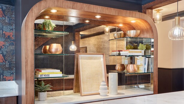 A reception area with a wooden arch, shelves with books and decorative items, and a marble counter. - The Davis Downtown San Diego (San Diego)