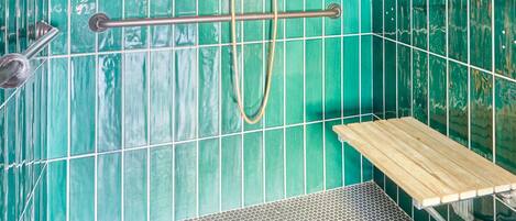 Ducha con cabezal de ducha y grifo de mano, estante de madera y asiento de ducha metálico.