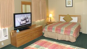 Habitación de hotel con una cama, un televisor sobre un tocador, una lámpara y un cuadro en la pared.
