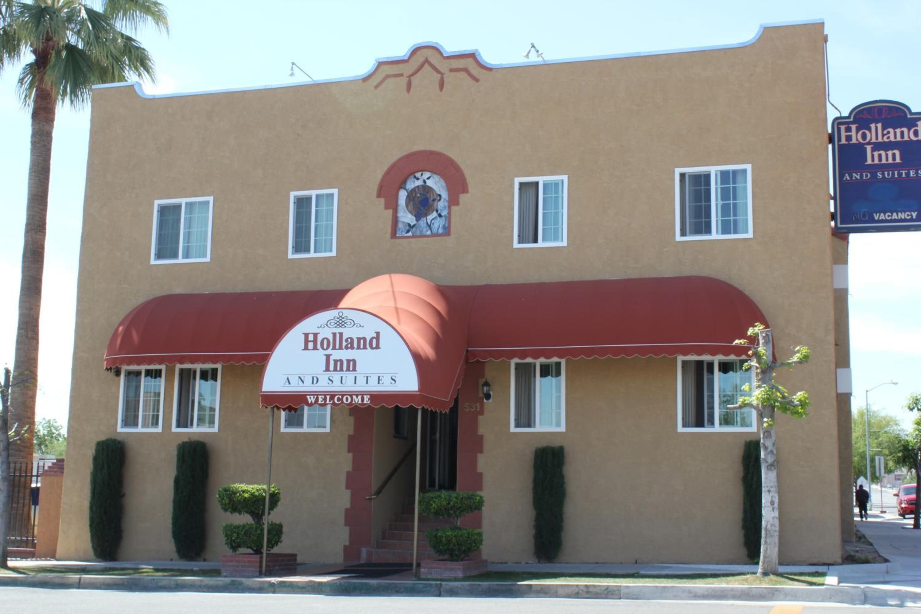 A two-story building with a red awning and a sign that reads "Holland Inn and Suites."