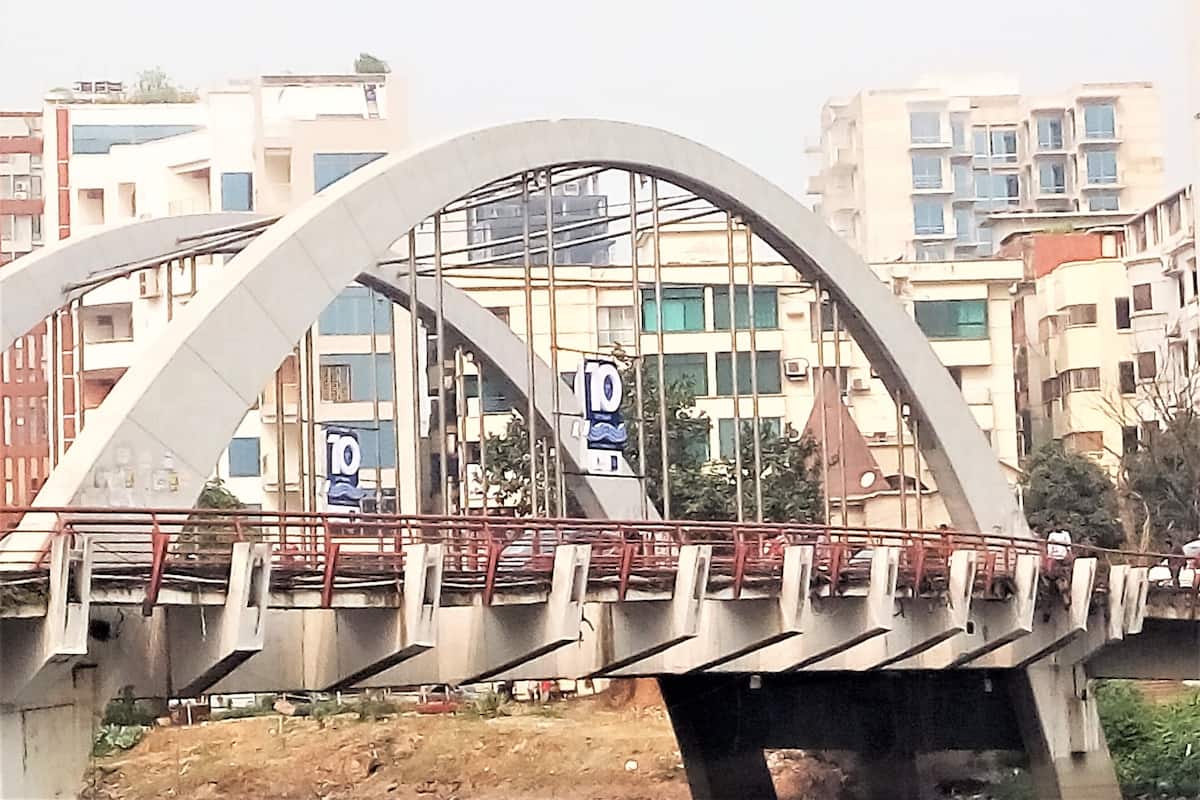A pedestrian bridge with a curved design, metal railings, and a series of numbered signs.