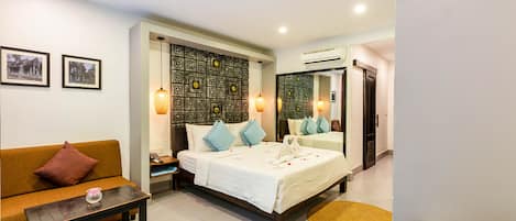 Quarto de hotel com uma cama, um sofá, uma mesinha e um espelho.