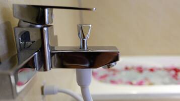 A bathroom with a chrome faucet and a white cable running to a device.