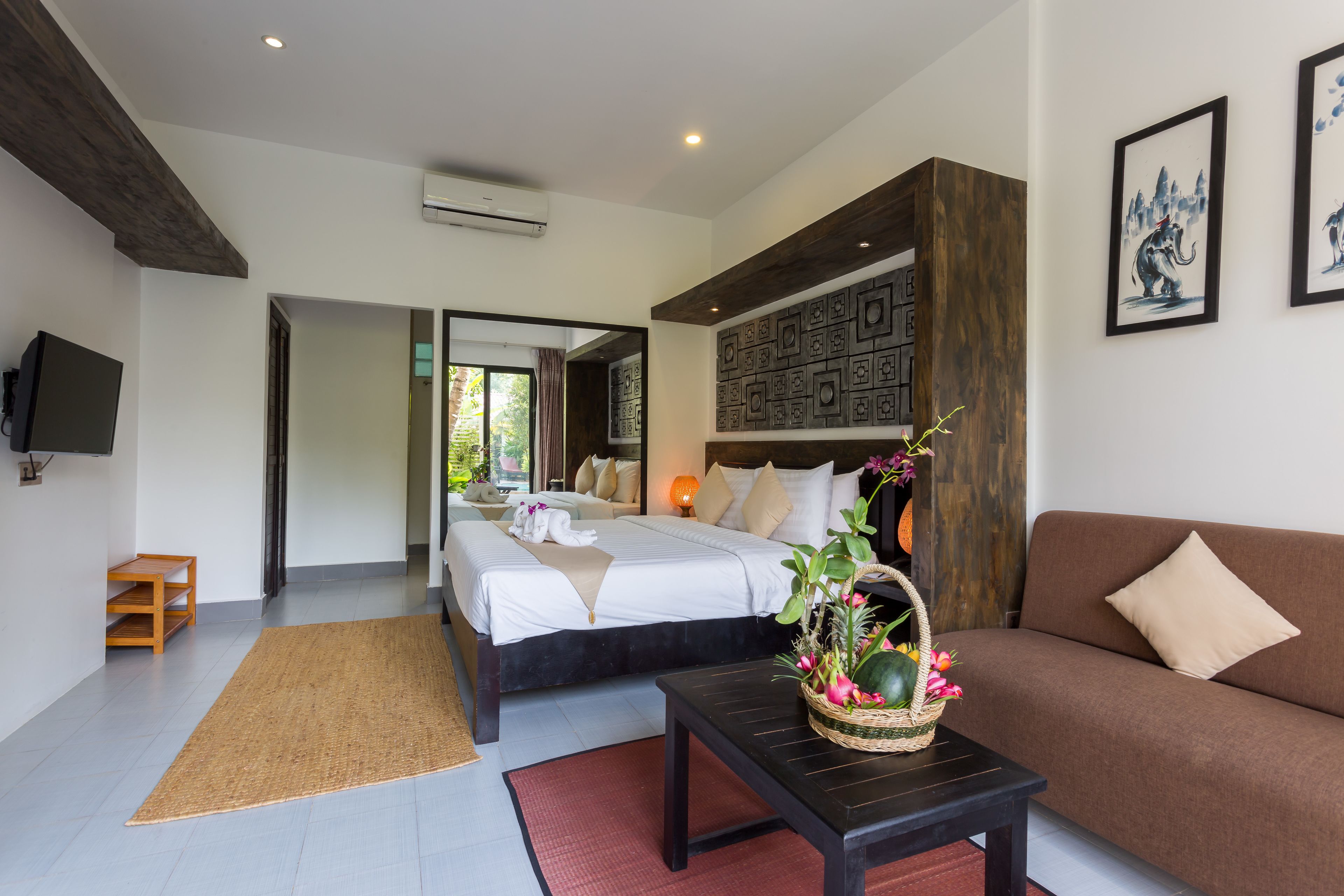 A modern bedroom with a large bed, a sofa, a TV, and a decorative wall panel.