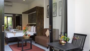 Une chambre d’hôtel avec un lit, un canapé, une table à manger et une chaise. Il y a une fenêtre donnant sur un paysage verdoyant.