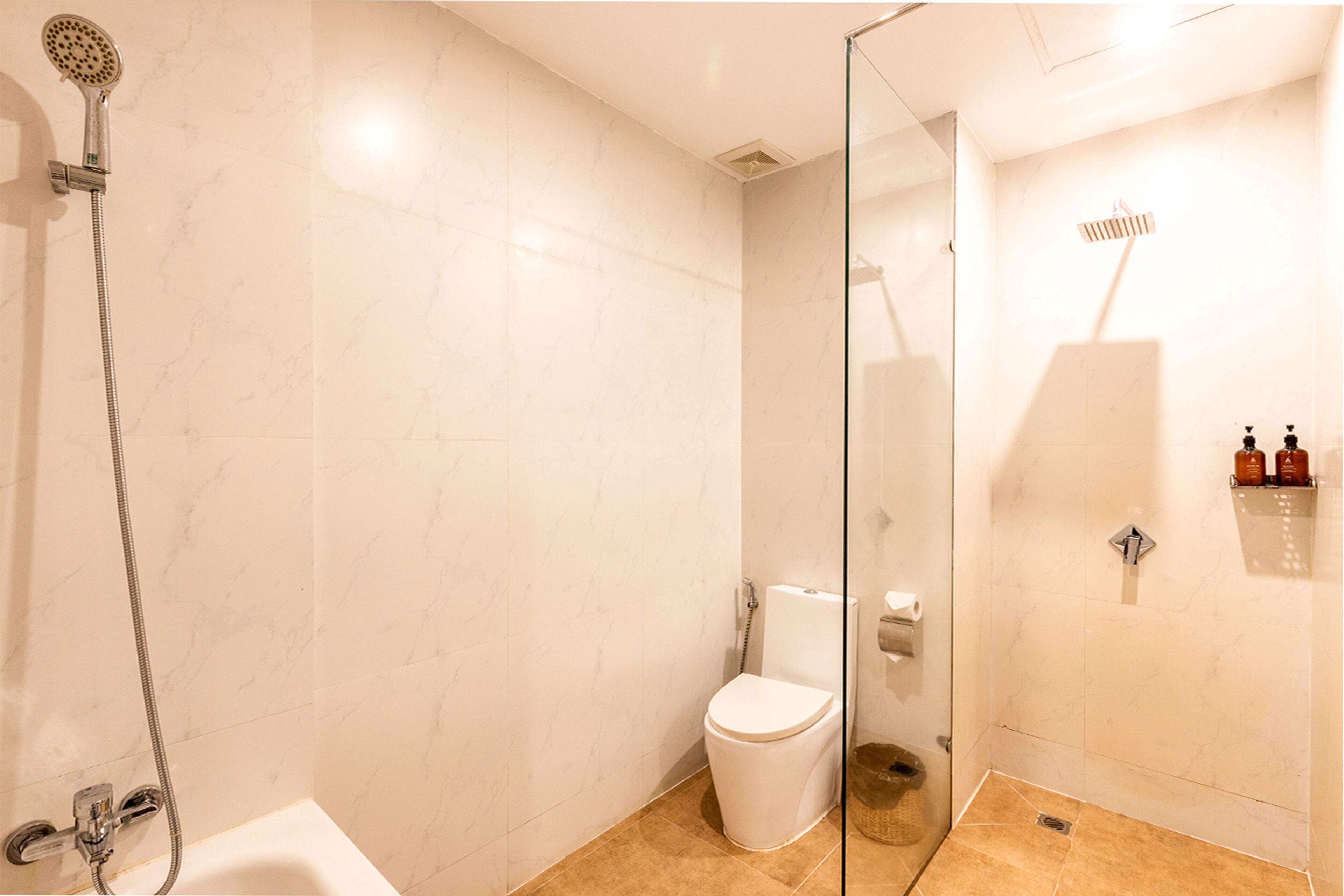 A modern bathroom with a glass shower enclosure, a white toilet, and a bathtub.