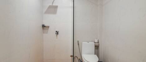 A small, enclosed shower area with a glass door, a white toilet, and a showerhead.