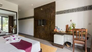 A hotel room with a bed, a desk with a chair, a television, and a small refrigerator.