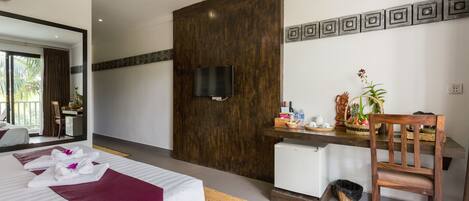 A hotel room with a bed, a desk with a chair, a television, and a small refrigerator.