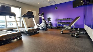 Un gimnasio con cintas de correr, elípticas y bancos de pesas.