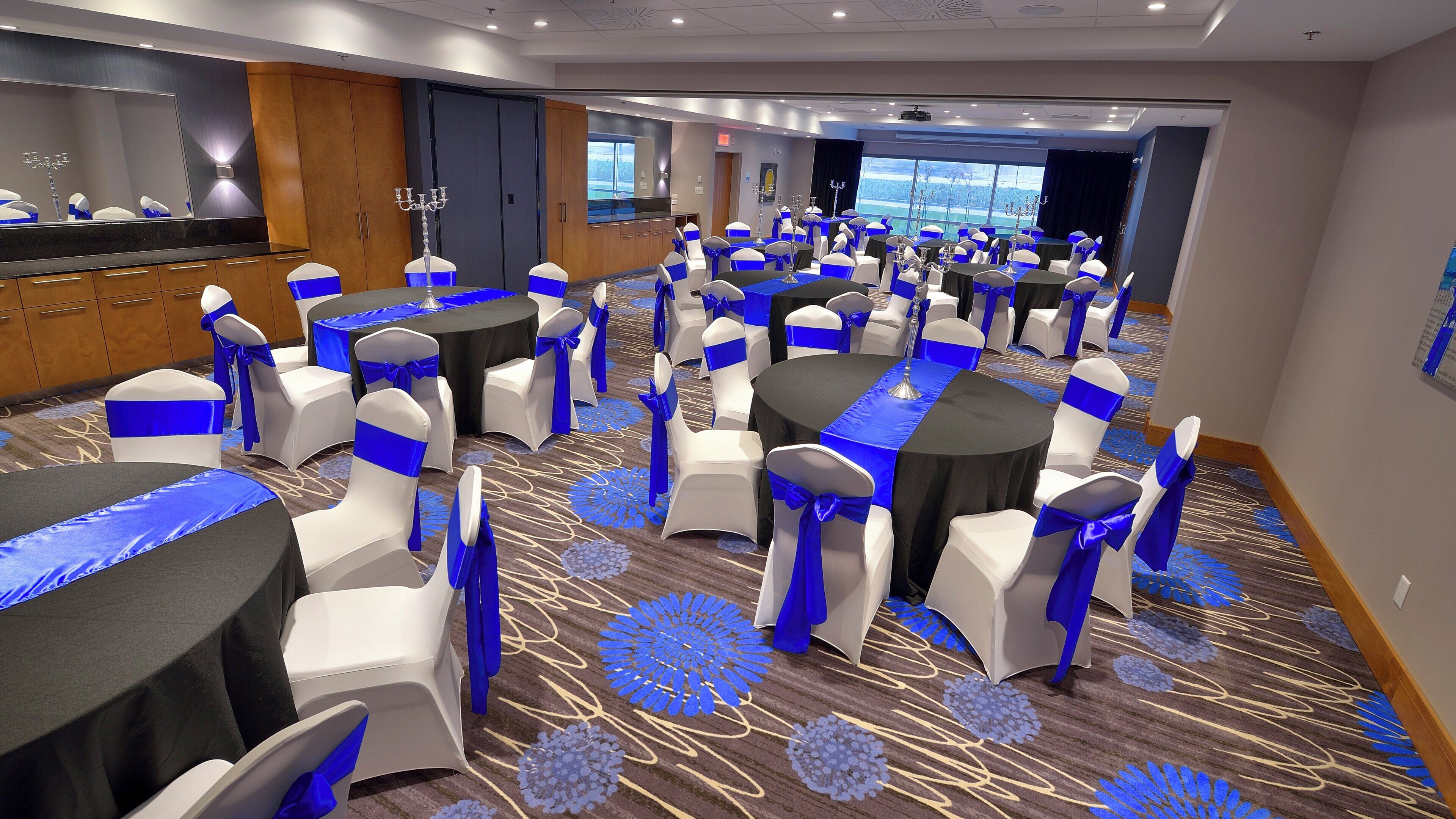 A conference room with round tables, white chairs, and blue sashes.