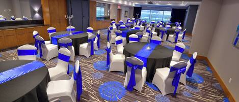 A conference room with round tables, white chairs, and blue sashes.