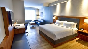 Une chambre d’hôtel avec un grand lit, un bureau avec une chaise, un canapé et un téléviseur.
