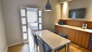 A modern kitchen with a dining area, wooden cabinets, a microwave, and a flat-screen TV.