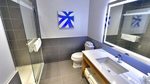 Une salle de bain moderne avec une douche à parois de verre, des toilettes blanches et un grand miroir au-dessus du lavabo.