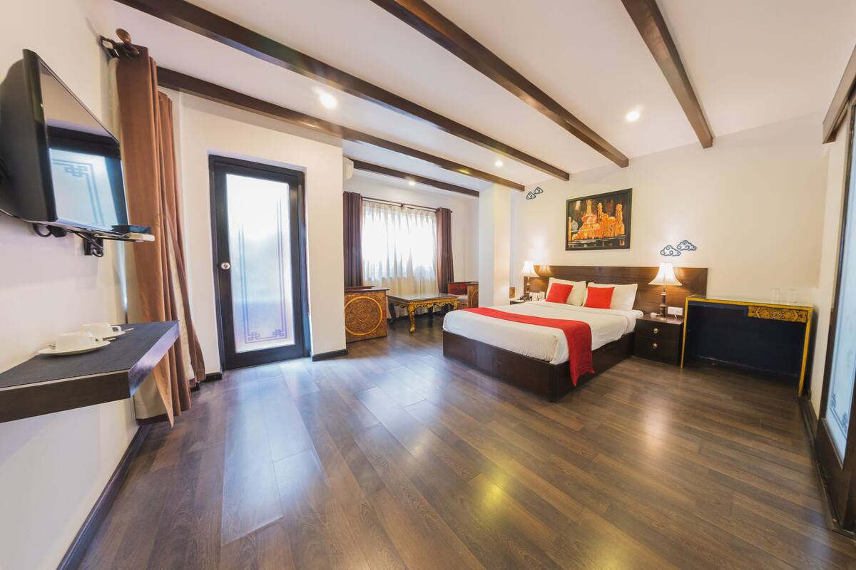 Une chambre d’hôtel spacieuse, dotée d’un grand lit, de tables de chevet, d’une télévision et offrant une vue sur l’extérieur.