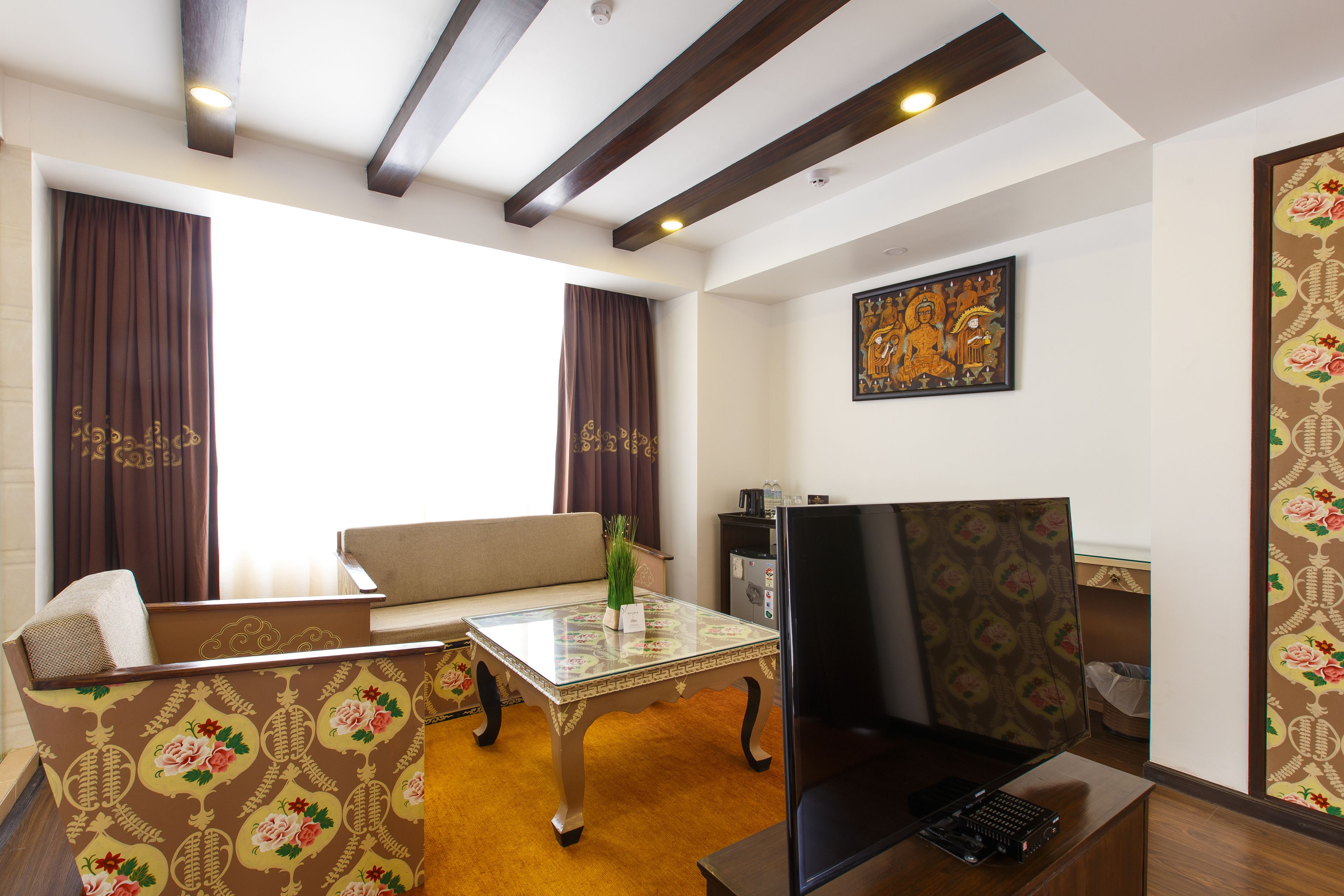 A living room with a sofa, a glass-top coffee table, a television, and a patterned wall.