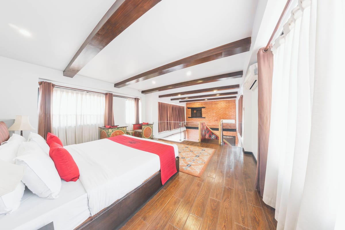 Une chambre d’hôtel avec un grand lit, un plancher en bois, un coin repas et un mur en briques.