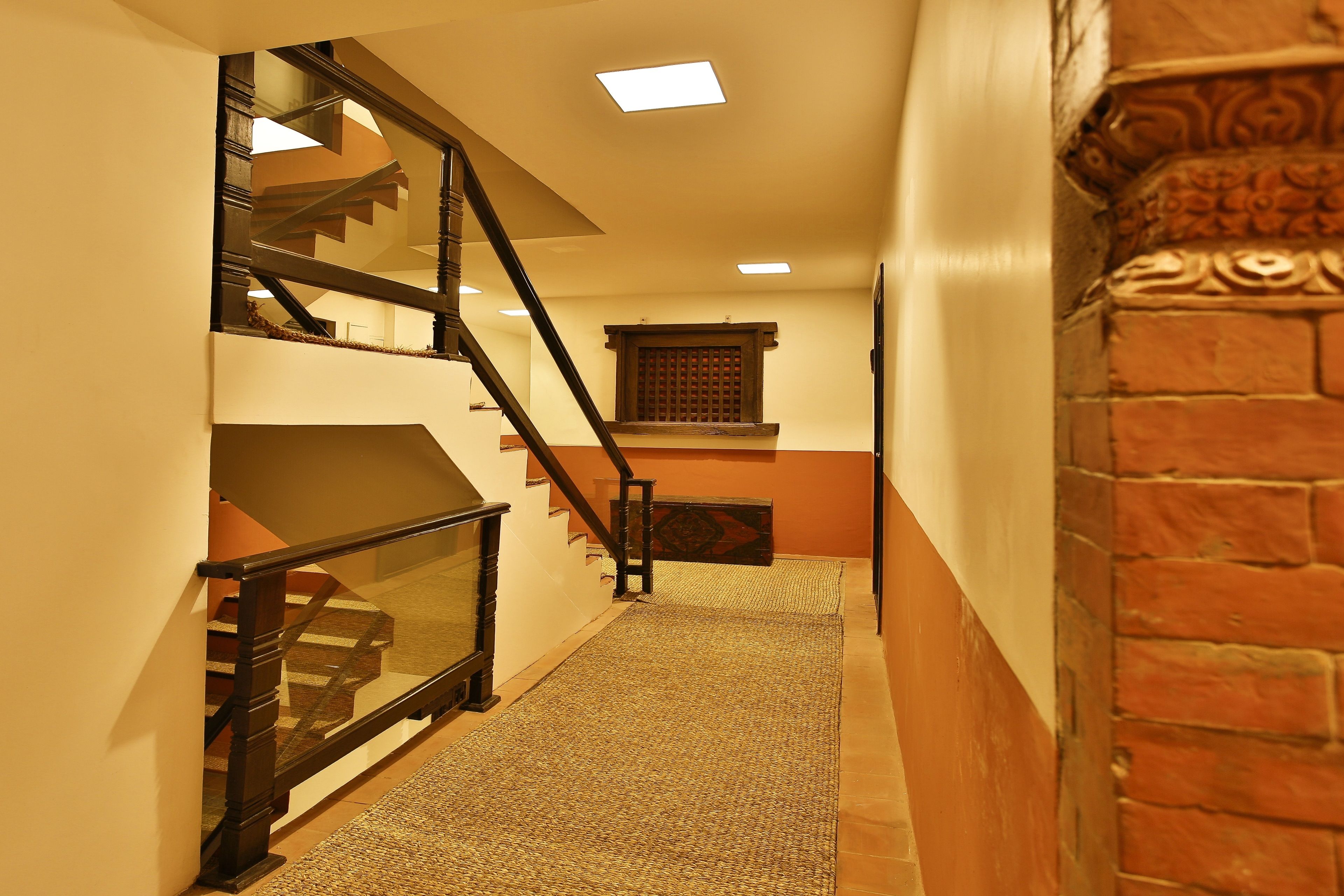 A staircase with a wooden handrail and a carpeted landing.