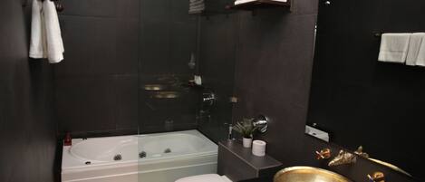 Un baño moderno con bañera, inodoro y un lavamanos grande.