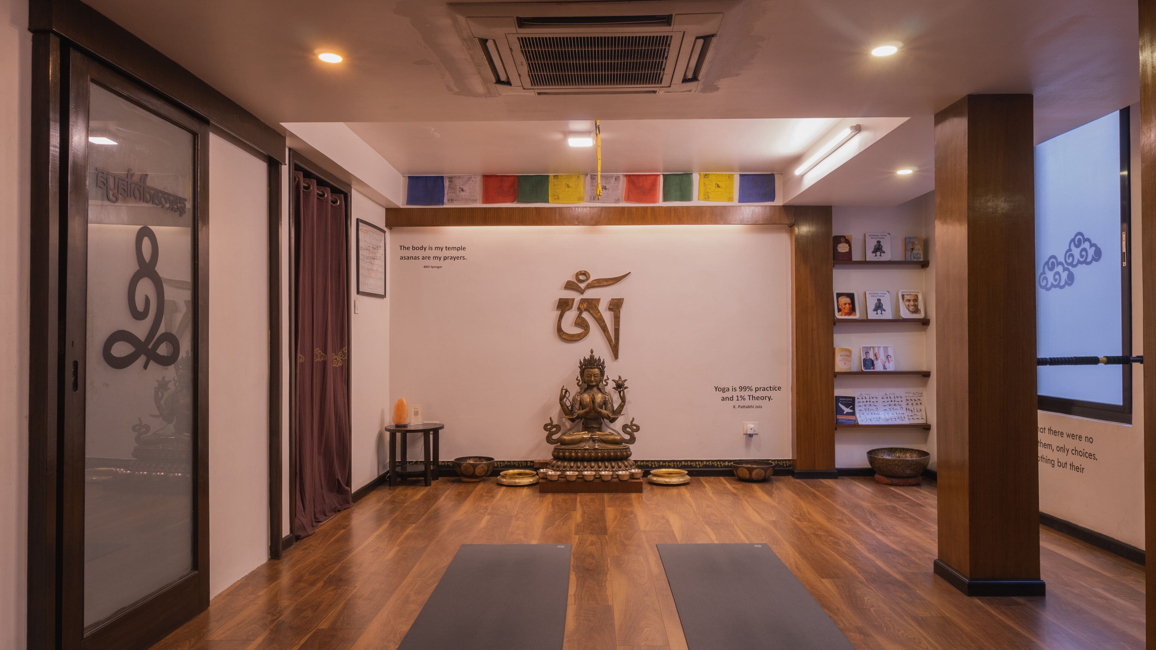 Un studio de yoga doté d’un plancher en bois, d’une statue et d’un mur orné de citations et de symboles inspirants.