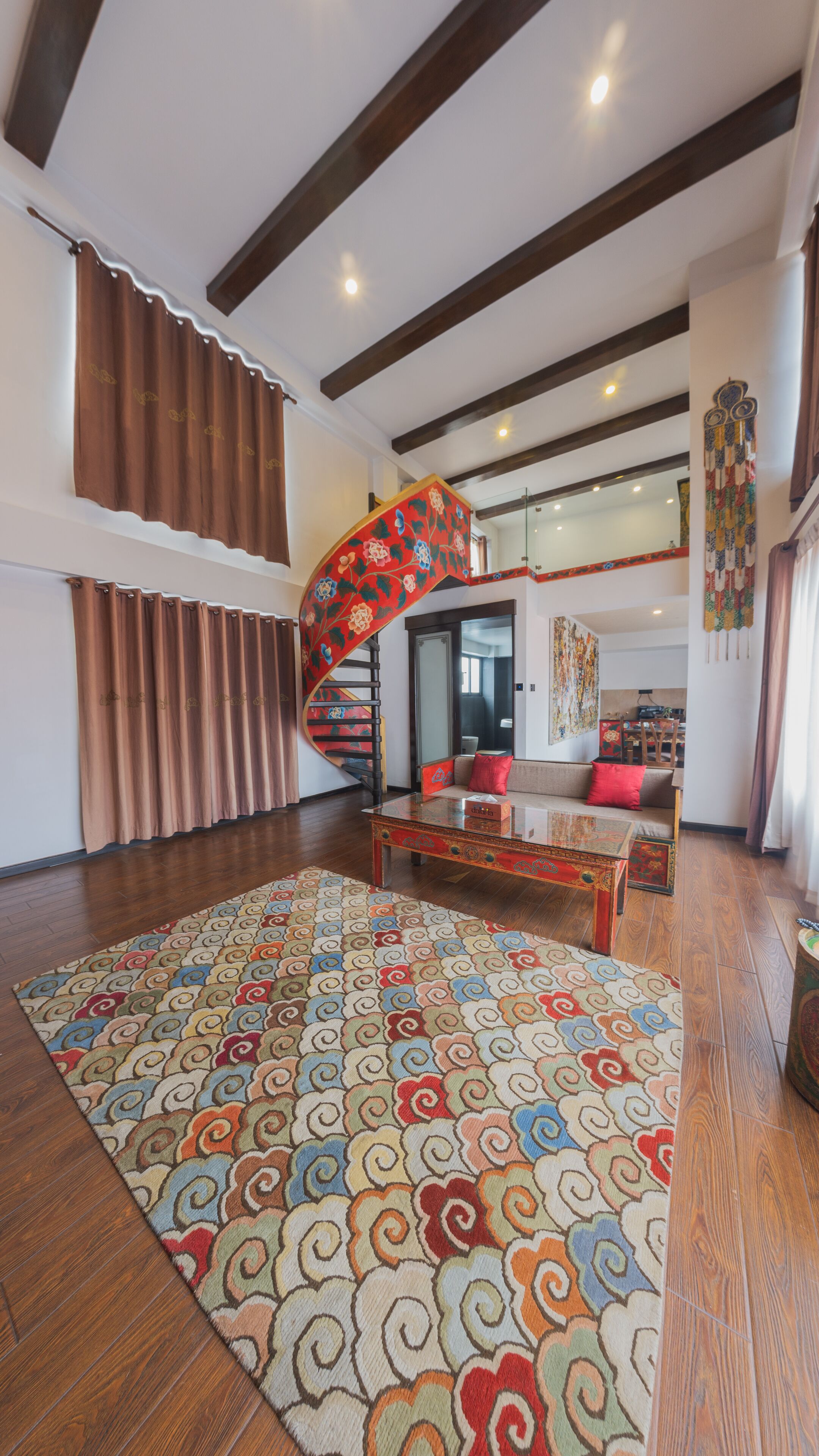 Un salon spacieux agrémenté d’un grand tapis à motifs, d’une table basse en bois et d’un escalier en colimaçon.