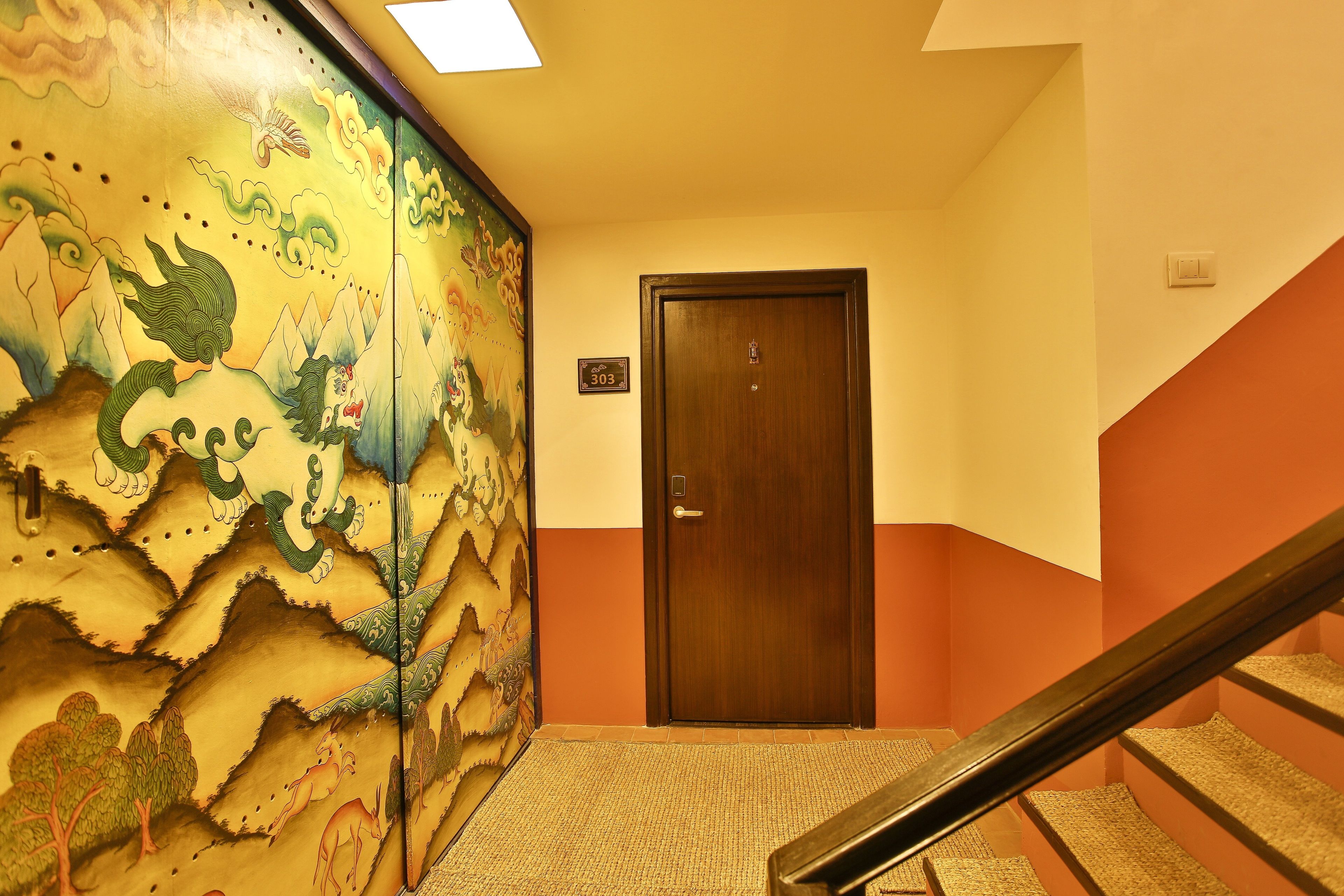 A hallway with a wooden door marked 303, a carpeted floor, and a staircase with a handrail.