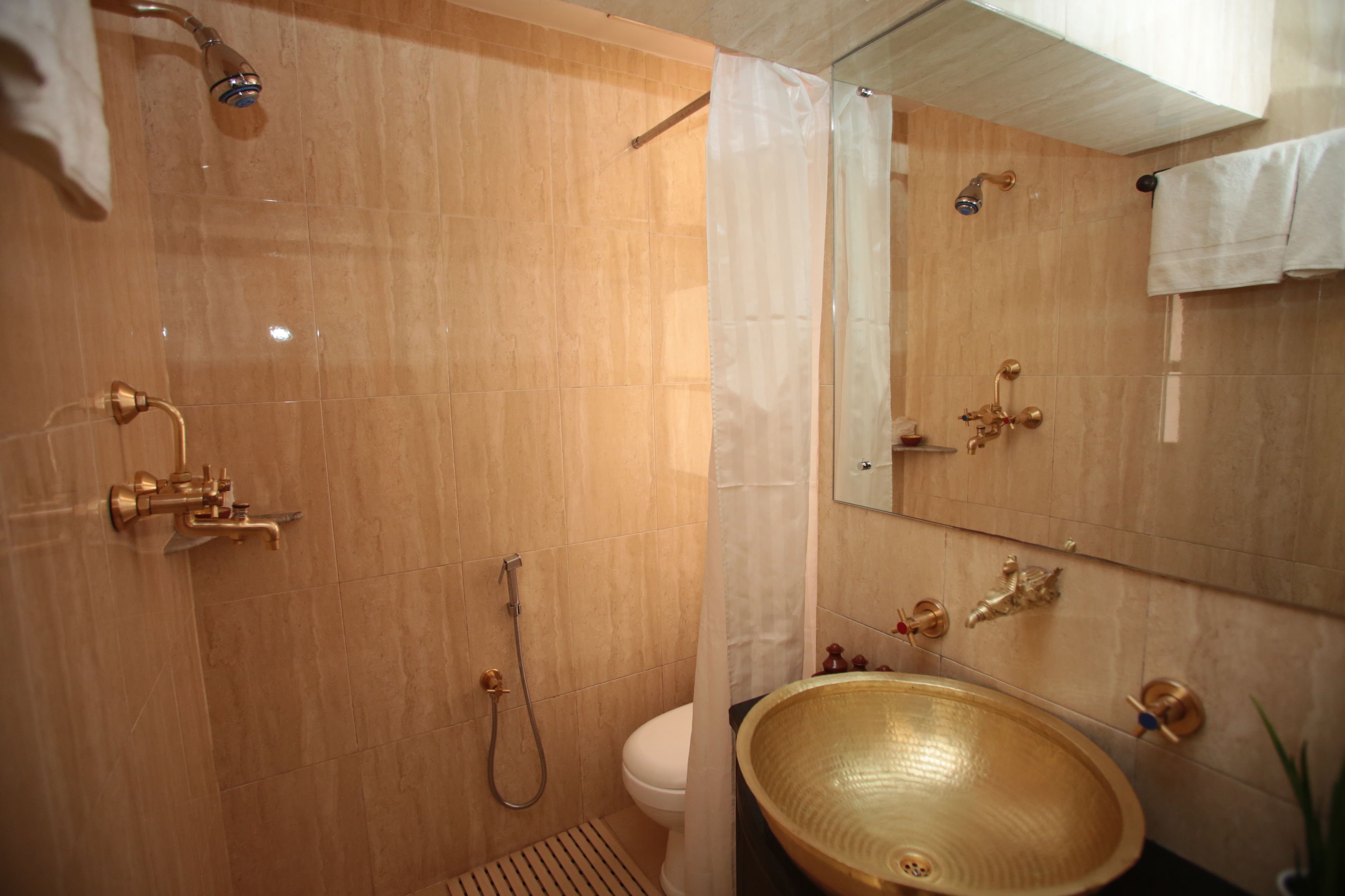 A bathroom with a shower, toilet, and a large basin sink.