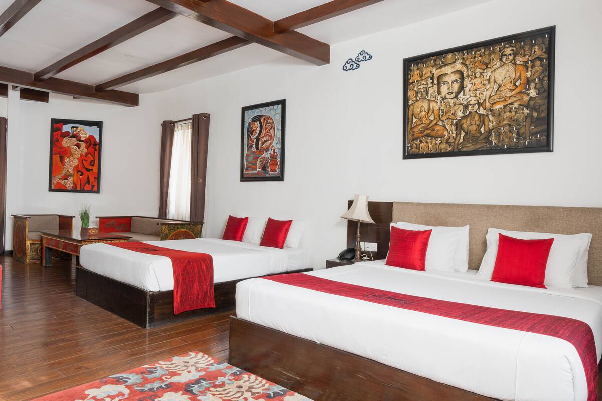 Une chambre d’hôtel avec deux lits, un grand tableau et un plafond en bois.