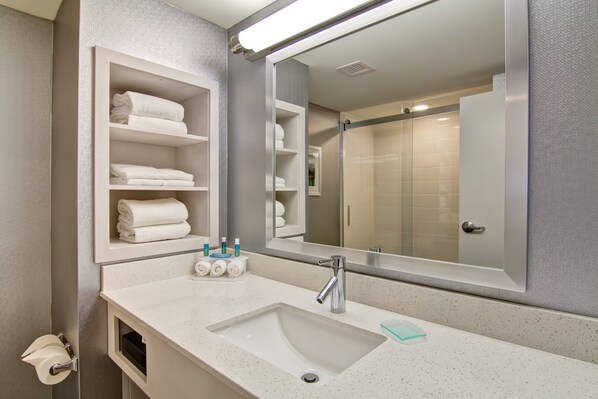 A modern bathroom with a large mirror, a white sink, and shelves with neatly folded towels. - Holiday Inn Express & Suites Oshawa Downtown - Toronto Area by IHG (Oshawa)
