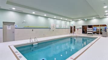 An indoor swimming pool with clear water, marked lanes, and safety signs.